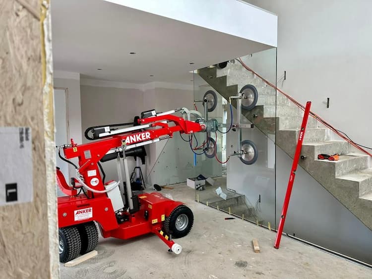 Red SL 608 vacuum lifter installing large glass panel by stairs